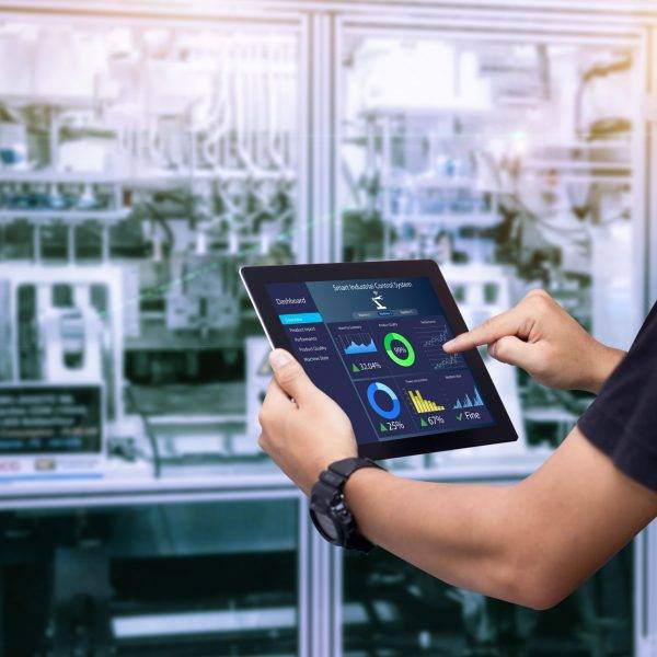 Smart industry control concept.Hands holding tablet on blurred automation machine as background