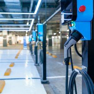 Electric car charging station for charge EV battery. Plug for vehicle with electric engine. EV charger. Clean energy. Charging point at car parking lot. Green power. Future transport technology.